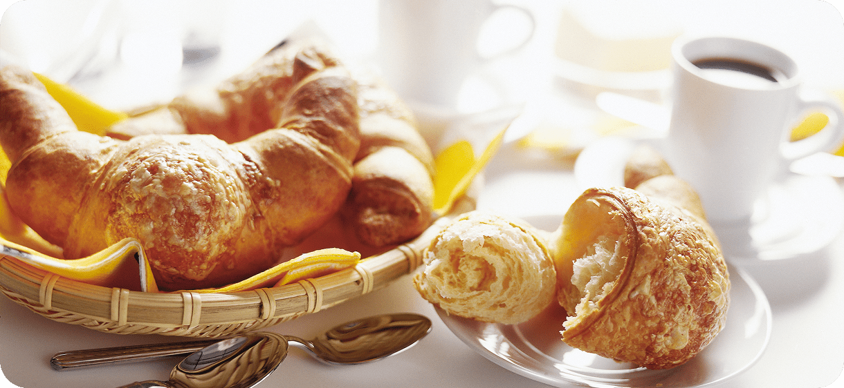 Fresh croissants with coffee on table