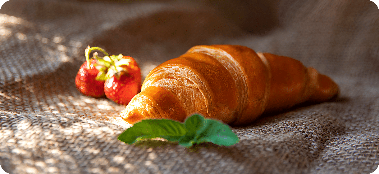 Croissant and strawberries on textured fabric